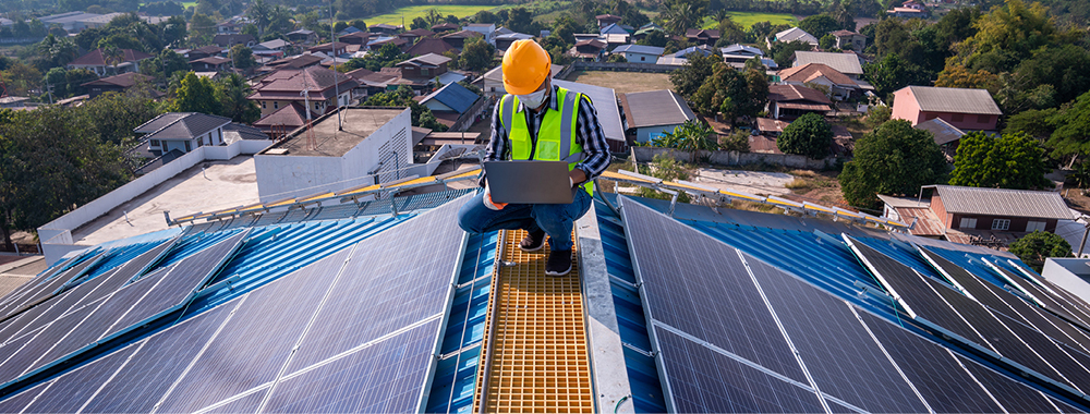 working installing solar panels on roof of building