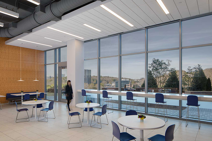 Modern office cafeteria with tables and large glass windows