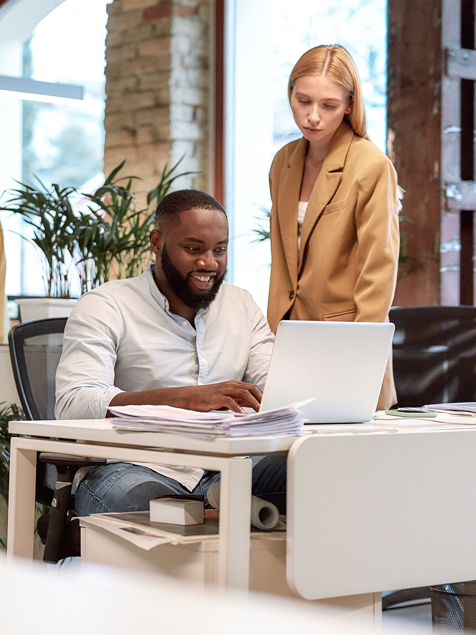 Employees in a flexible office coworking space gathered around hot desk.